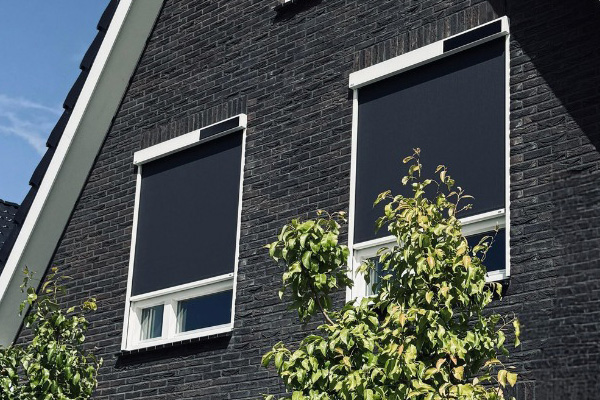 Donkere buitenscreens van VABO bij moderne woning voor zonwering en privacy